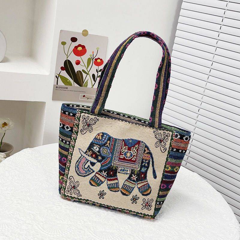 Cream and tan tote bag with a woven elephant motif